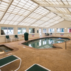 Indoor pool under glass windows near lounge chairs and hot tub in Ogunquit, ME