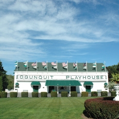 Ogunquit Playhouse exterior with flags over entrance in front of large lawn in Ogunquit, ME