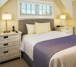 Double Bed at Coastal Maine Hotel with White Linens, Blue Blanket and Yellow Walls