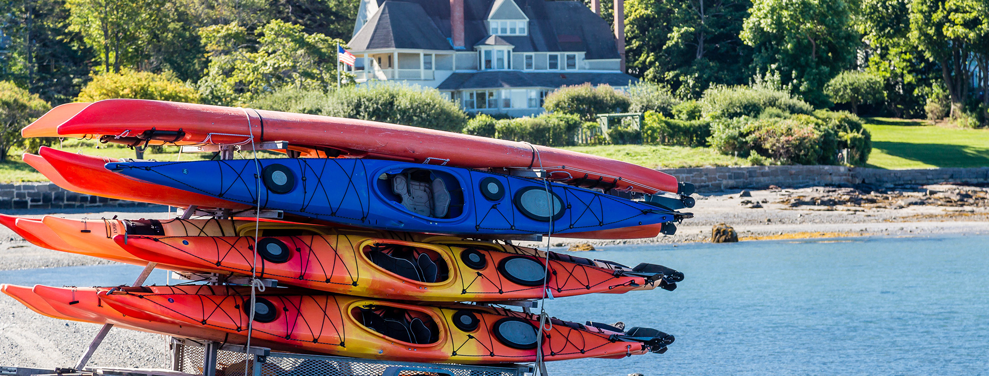 Rack of different colored kayaks in front of beach near Ogunquit, ME hotel near ocean