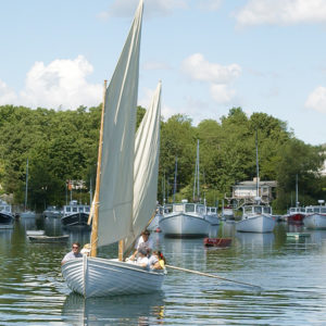 Sailboat with people in it on water near other boats in harbor in Ogunquit, ME